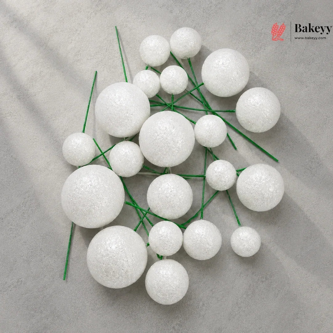 White spherical decorations on green stems with Bakeyy logo in the corner