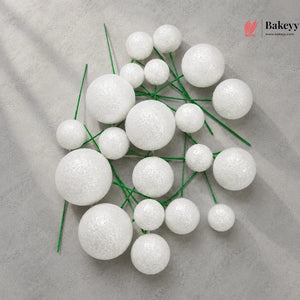 White spherical decorations on green stems with Bakeyy logo in the corner