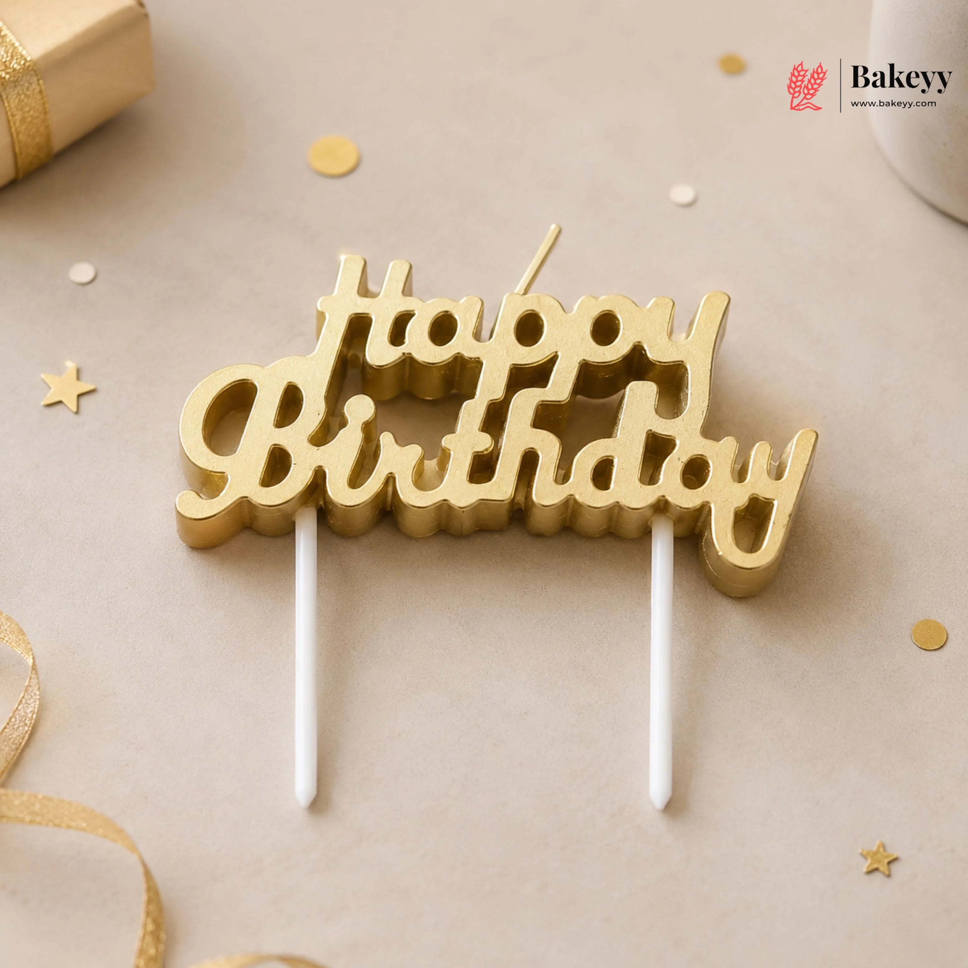 Gold 'Happy Birthday' cake topper on a neutral background with decorative elements.