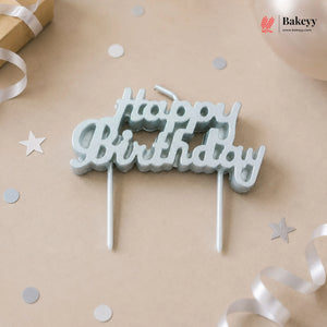 Silver 'Happy Birthday' candle topper on a beige background with confetti and ribbons.