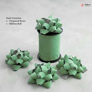 Green glittery bows and a roll of ribbon on a light gray background with 'Bakeyy' branding.