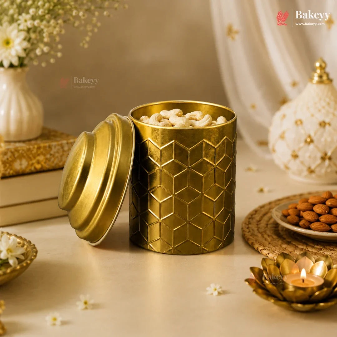 Gold textured container with cashews on a decorative table setting with candles and flowers.