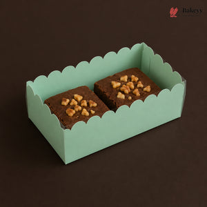 Two brownies with nuts in a green box on a dark background