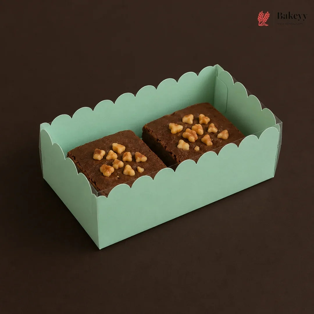 Two brownies with nuts in a green box on a dark background