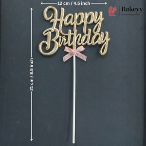 Gold cursive 'Happy Birthday' cake topper with a pink glitter bow on a white stick, shown on a dark background with printed dimensions and a Bakeey logo.