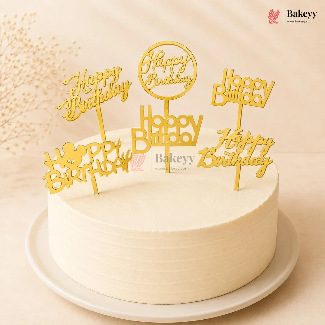 White cake with gold 'Happy Birthday' toppers on a beige background, featuring the Bakeyy brand.
