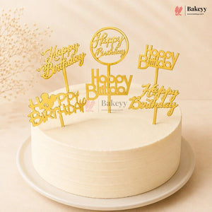 White cake with gold 'Happy Birthday' toppers on a beige background, featuring the Bakeyy brand.