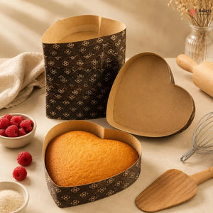 Heart-shaped baking pans with a cake, surrounded by baking tools and ingredients on a neutral background.