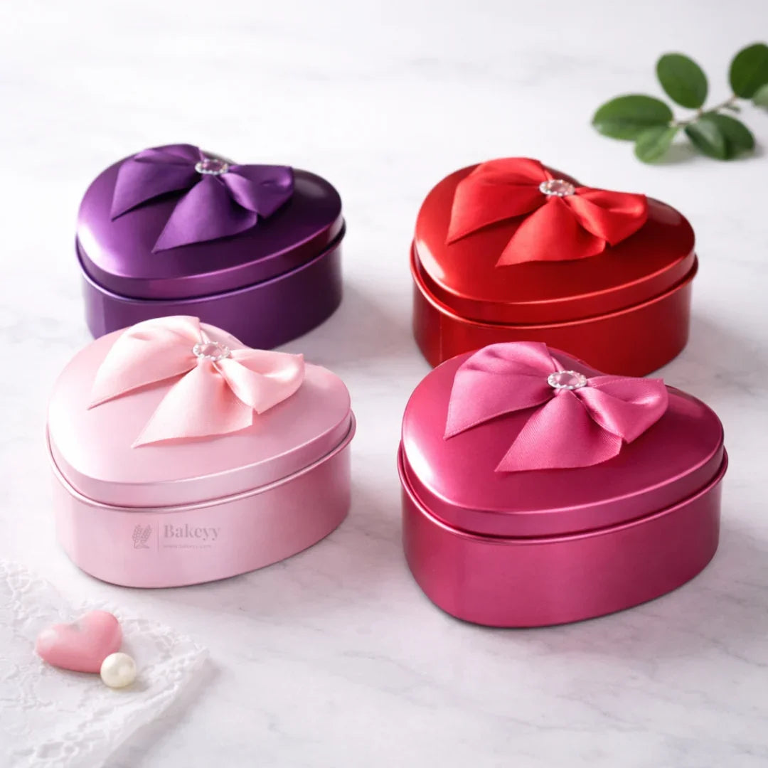 Heart-shaped tin gift boxes with bows in pink, red, purple, and magenta from Bakeyy