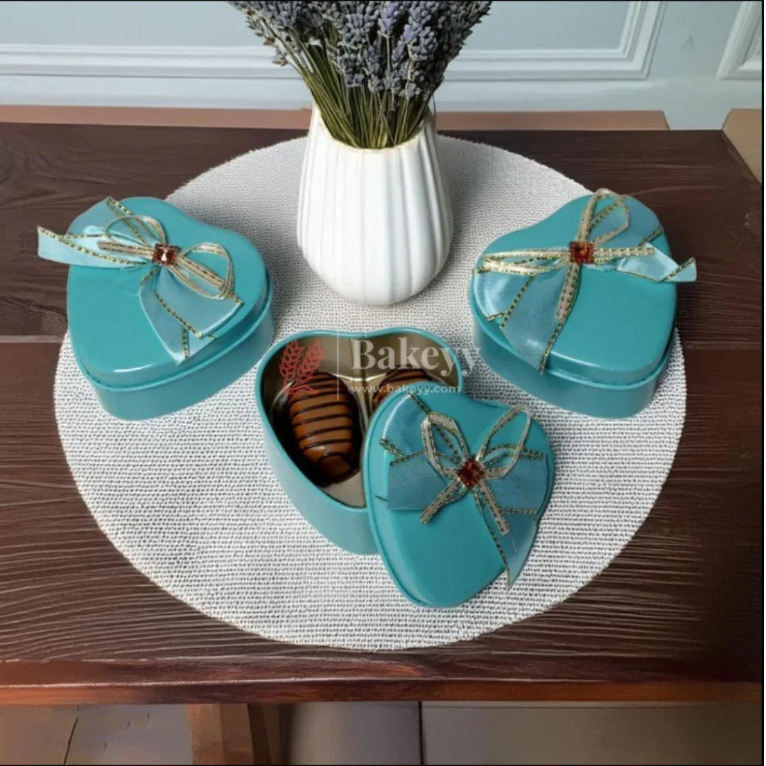 Blue heart-shaped tin gift boxes with bows from Bakeyy.com, displayed on a table.