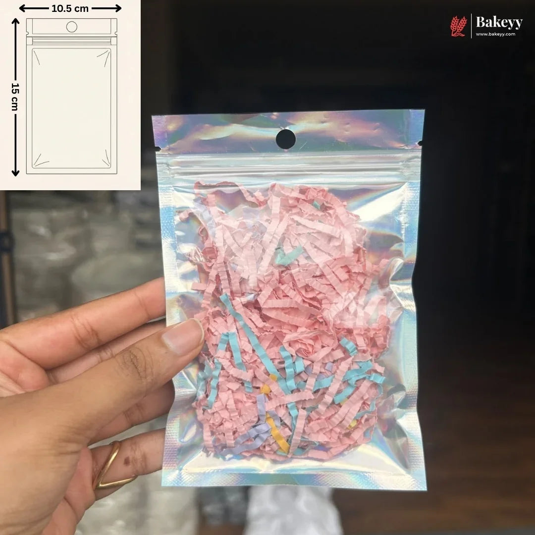 A hand holds a holographic silver resealable pouch filled with pink and blue shredded paper filler. The top-left corner shows a size diagram indicating 10.