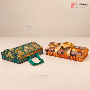 Two decorative rectangular gift boxes for baked goods on a beige studio background. The left box is teal with ornate gold and multicolor patterns and a teal handle.