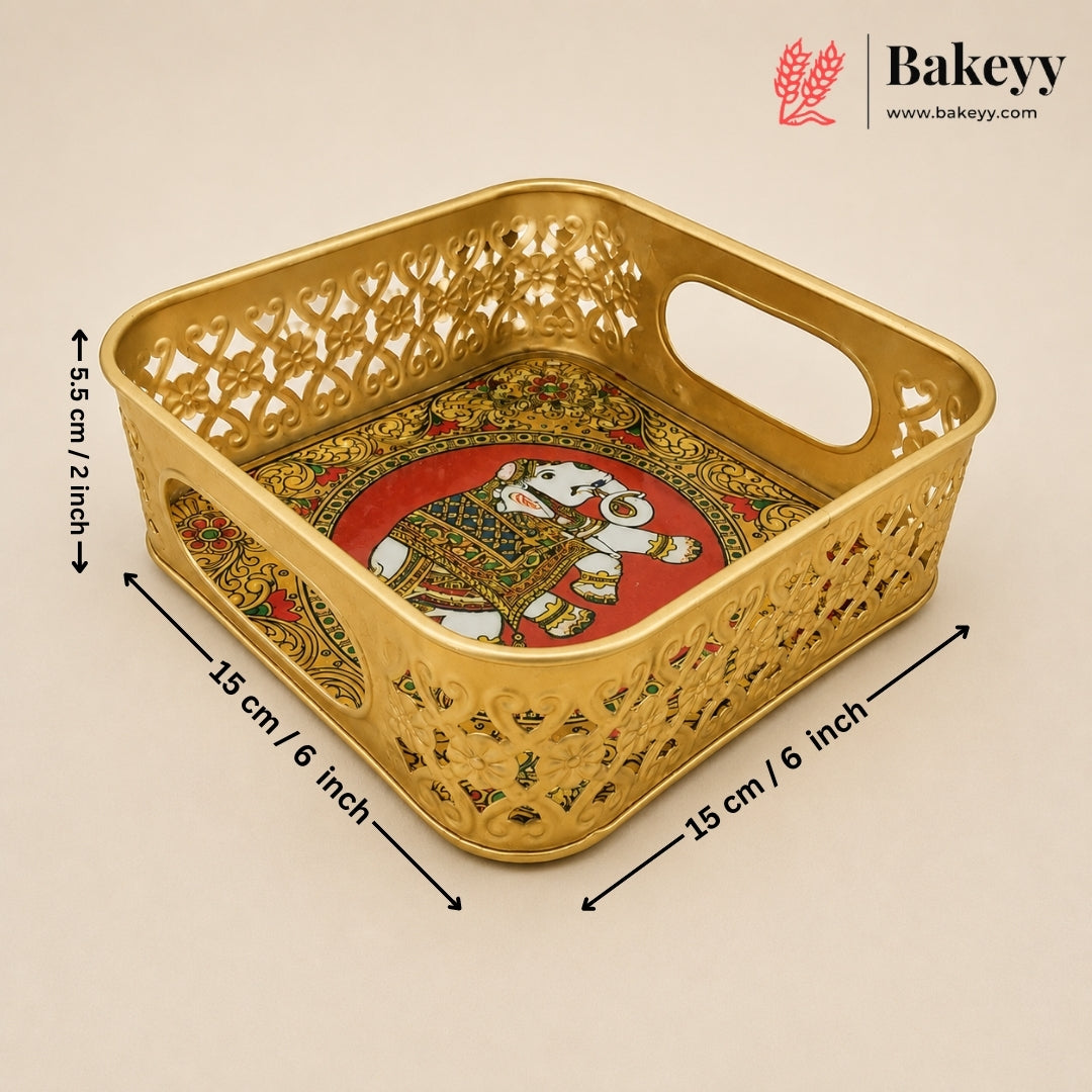 A gold-colored metal tray with intricate cutout patterns and a colorful elephant illustration on the bottom, shown on a beige background with dimension lines indicating its size.