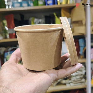 Brown paper cup with a lid held in a hand against a blurred store shelf background
