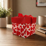 Red gift box with heart patterns on a wooden surface, featuring the Bakeyy brand.