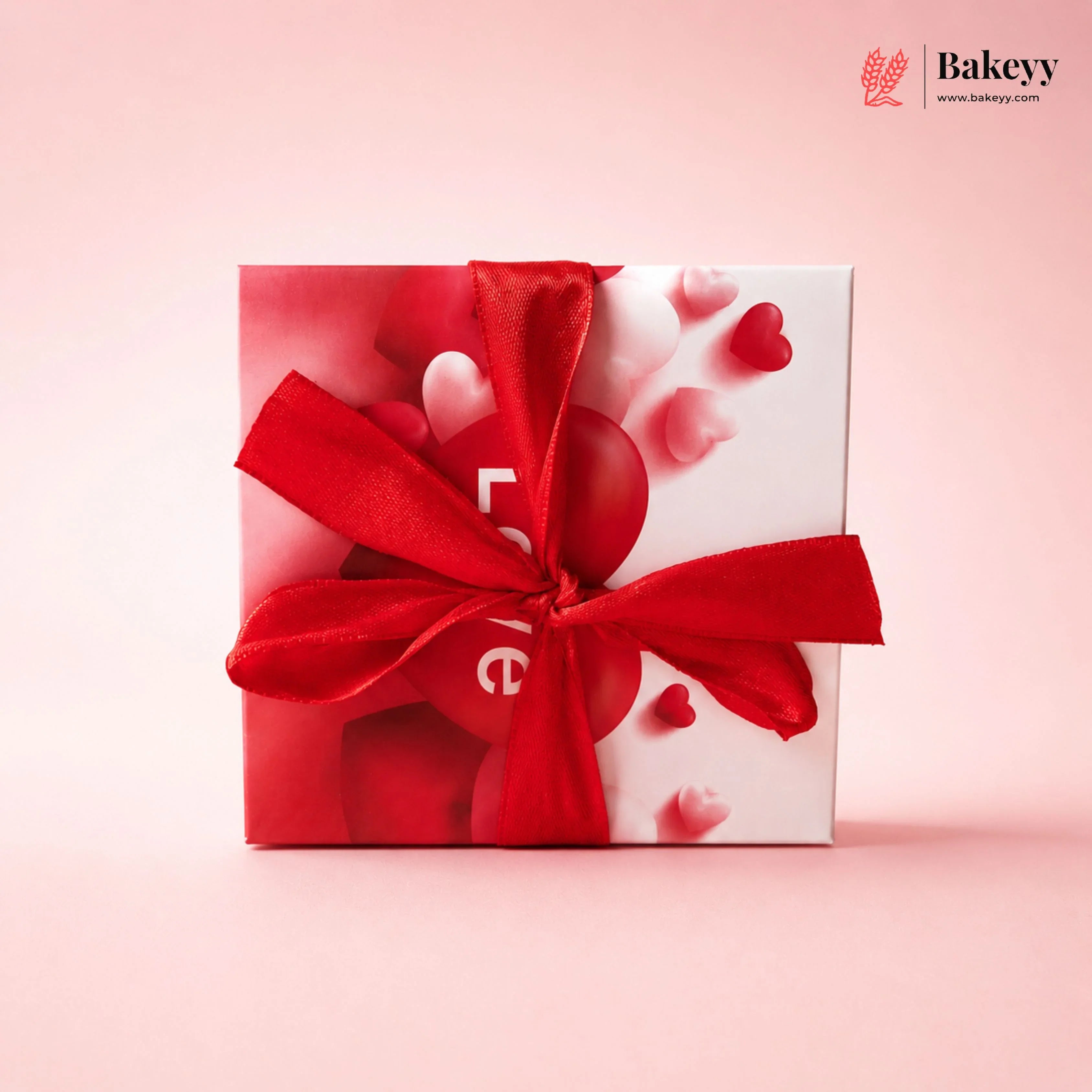 Gift box with a red ribbon on a pink background, featuring the Bakeyy brand.