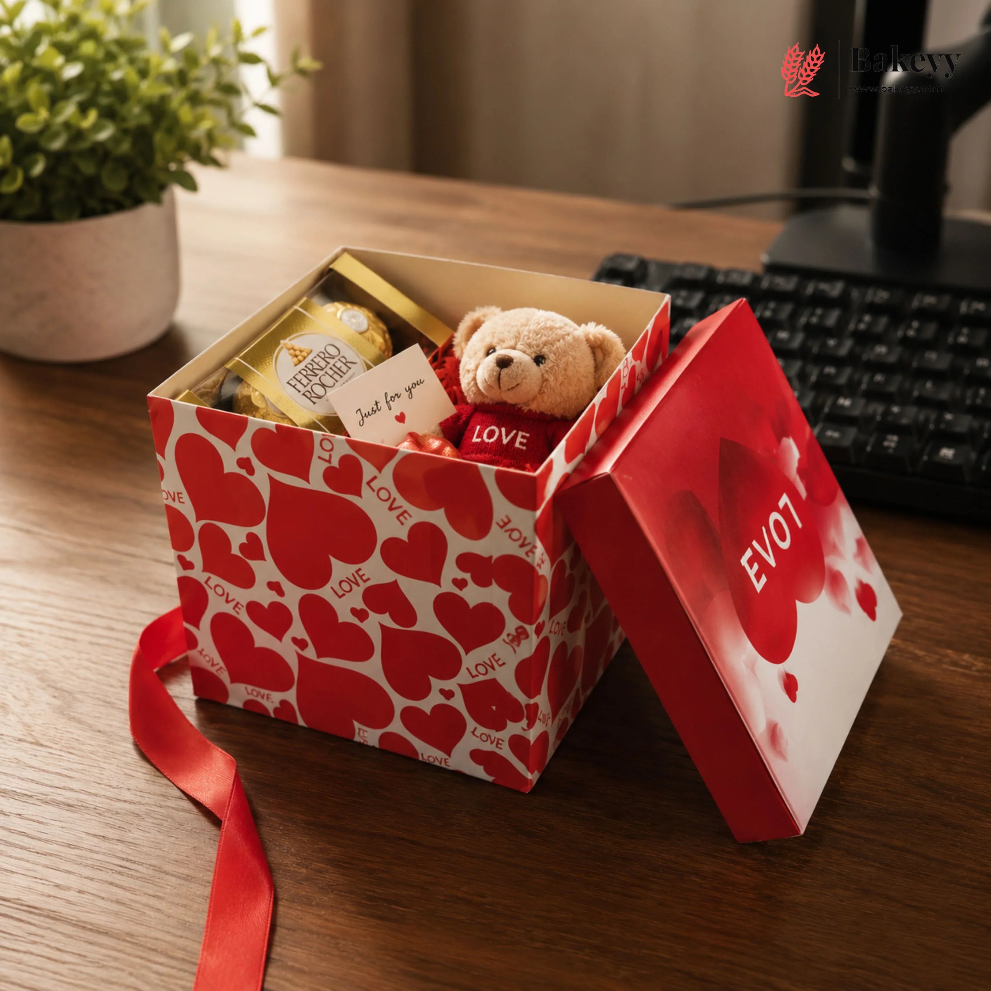 Open gift box with teddy bear and chocolates on a desk