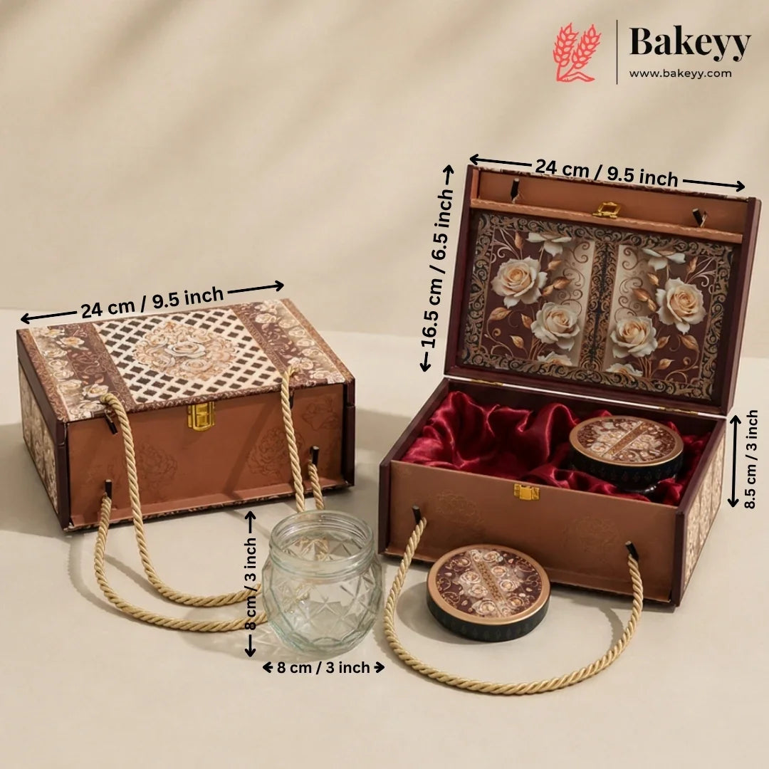 An ornate rectangular gift box set shown closed and open on a beige studio background, with measurement arrows and labels indicating dimensions. The set includes a brown patterned exterior box with rope handles, a matching open box with floral interior panels, red velvet lining, two round decorative containers, and a small clear glass jar.