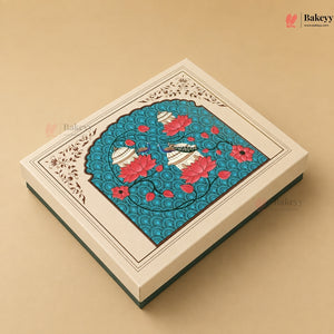 An ornate rectangular gift box with a cream-colored lid featuring a detailed central illustration of a peacock surrounded by pink lotus flowers on a turquoise background, set against a solid beige backdrop.