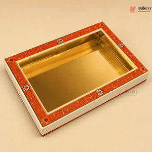 A rectangular gold-plated tray with an orange and white patterned border, shown on a beige background. The Bakeyy brand logo is visible in the top right corner.