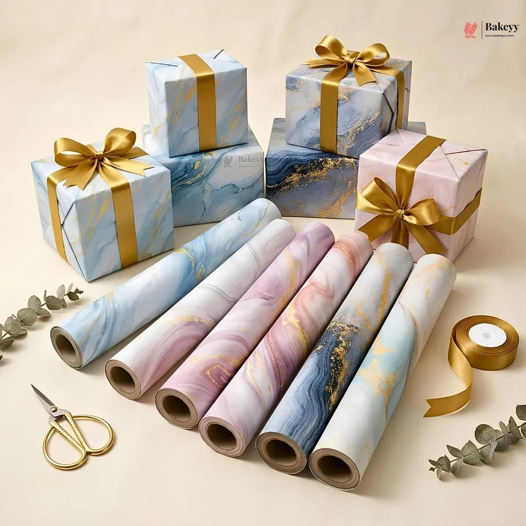 Marble-patterned gift wrap with gold ribbons and scissors on a beige background
