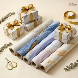 Marble-patterned gift wrap with gold ribbons and scissors on a beige background