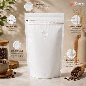A white stand-up pouch packaging bag with a heat seal and one-way valve, shown with callout graphics and text explaining its features. The background is a warm, styled kitchen or cafe setting with coffee beans, a jar, and a wooden scoop.