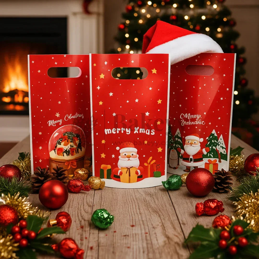 Three red gift bags with Christmas designs on a wooden table with festive decorations.
