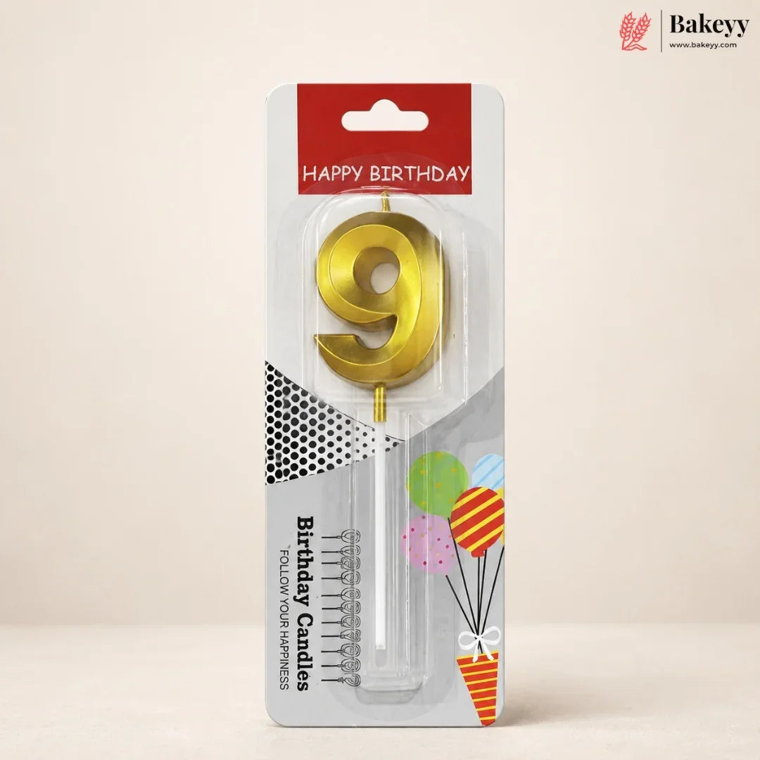 A gold metallic number 9 birthday candle in its original retail packaging, featuring a red 'HAPPY BIRTHDAY' header and festive balloon graphics on a beige background.
