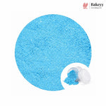 A large circular close-up of bright light blue powder, with a small inset showing the powder in a clear plastic jar. The Bakeyy logo appears in the top right on a white background.