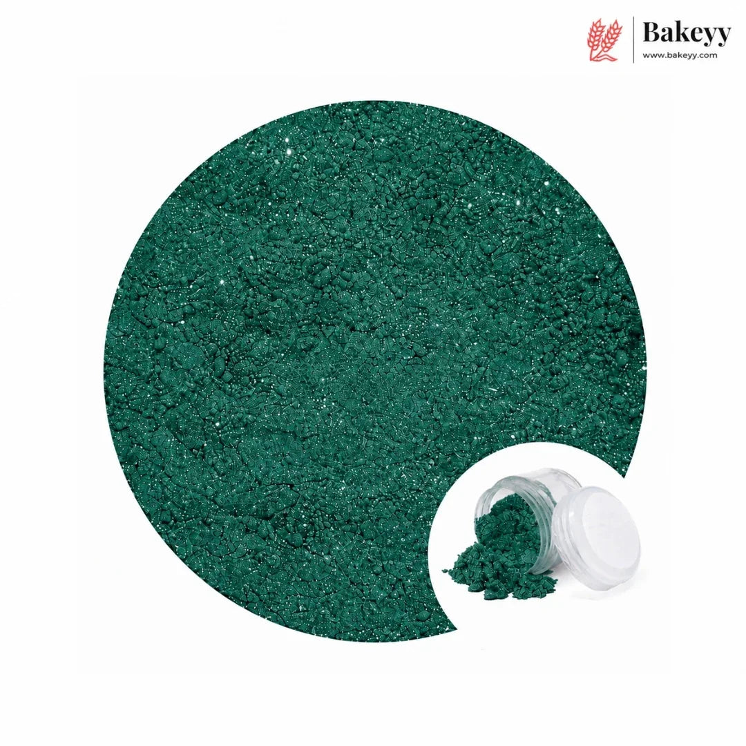 A circular close-up of sparkling dark green glitter powder, with a small inset showing the powder spilled from a clear jar with a white lid. The Bakeyy logo appears in the top right on a white background.