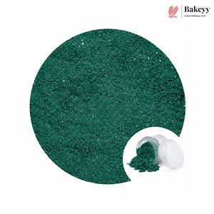 A circular close-up of sparkling dark green glitter powder, with a small inset showing the powder spilled from a clear jar with a white lid. The Bakeyy logo appears in the top right on a white background.