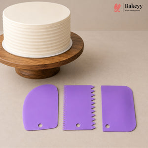 Three purple silicone cake scrapers displayed on a beige surface, with a partially decorated round cake on a wooden stand in the background. The Bakeey logo is visible in the top right corner.