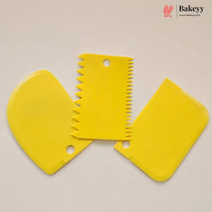 Three yellow plastic cake decorating tools, including two spatulas and one serrated scraper, arranged on a light beige background with a Bakeyy logo in the top right corner.