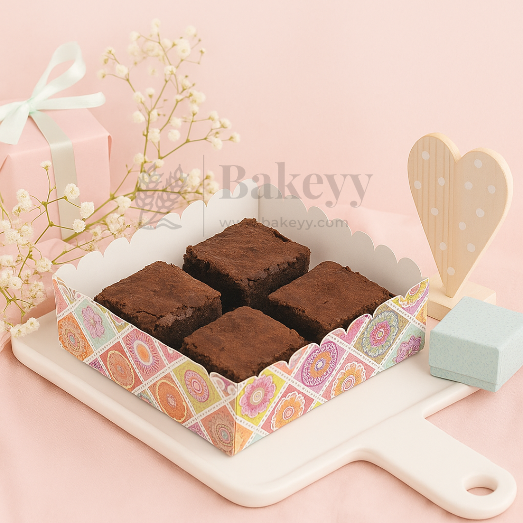 Brownies in a decorative box on a pink background with 'Bakeyy' branding.
