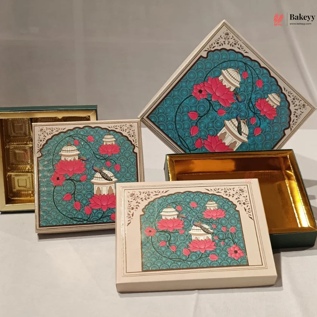 A set of decorative rectangular and diamond-shaped gift boxes with ornate teal floral designs, pink blossoms, and cream bird motifs, displayed on a white surface with one box open to reveal gold-toned interior compartments.