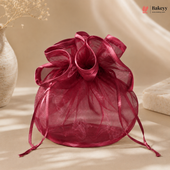 Pink organza drawstring bag on a beige surface with a soft focus background
