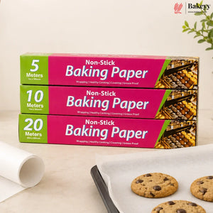 Three boxes of non-stick baking paper in different quantities (5 meters, 10 meters, and 20 meters) stacked on a light beige surface next to a partially unrolled white sheet and a baking tray with chocolate chip cookies. The Bakey brand logo is visible in the top right corner.