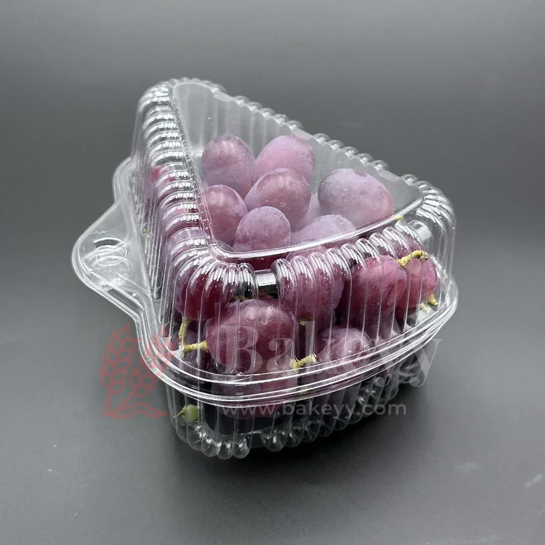 Clear plastic container with red grapes on a gray background