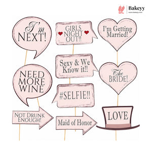 Set of pink photo booth props with wedding-themed sayings on a white background.