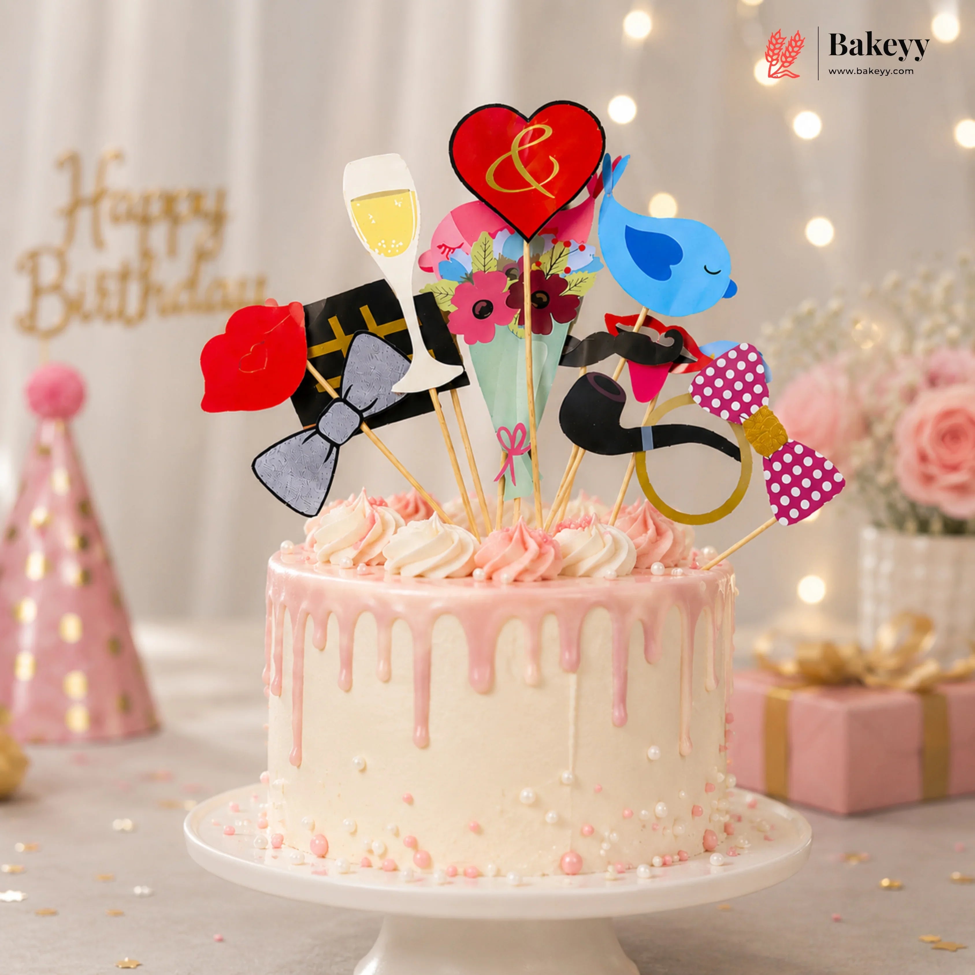 Decorative birthday cake with colorful toppers on a white plate, with 'Bakeyy' branding in the background.