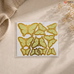 Pack of butterfly-shaped stickers on a beige surface with a natural background
