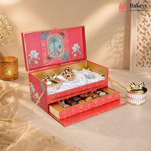 An ornate red and gold gift box set with floral patterns, shown open to reveal decorative chocolates and sweets inside, alongside a matching small container on a beige tabletop with warm ambient lighting.