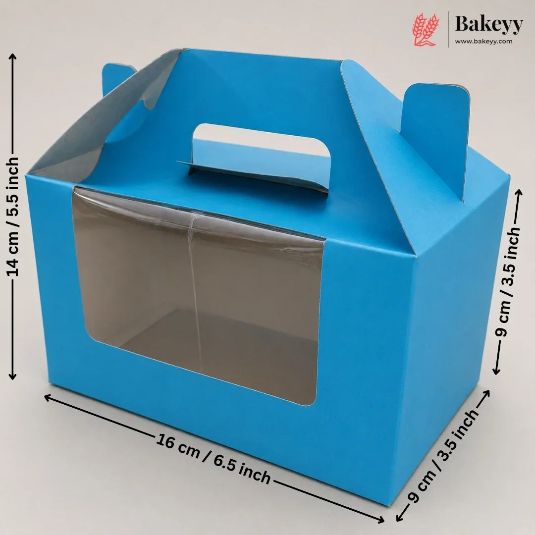 Blue bakery gift box with a clear front window and top handle, shown with dimension arrows and labels indicating 14 cm height, 16 cm width, and 9 cm depth on a light gray background. Bakeyy logo appears in the top right.