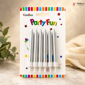 Pack of silver birthday candles with colorful packaging on a wooden surface.