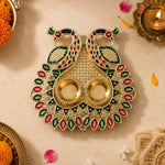 Decorative diya with peacock design on a beige background