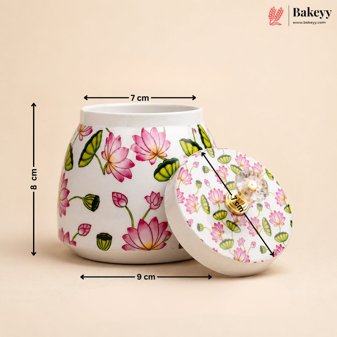 A white ceramic jar with a matching lid, decorated with a pink and green lotus floral pattern, shown with dimension lines indicating its height of 8 cm, top diameter of 7 cm, and base diameter of 9 cm. The Bakeey brand logo is visible in the top right corner.