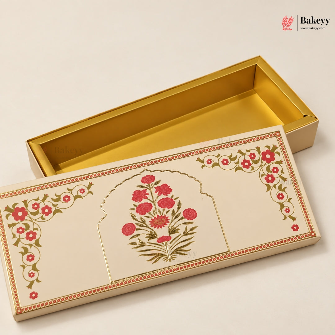 An ornate rectangular gift box with a cream-colored exterior decorated with red floral motifs and green leaves, shown alongside an open gold interior. The Bakeyy logo is visible in the top right corner.