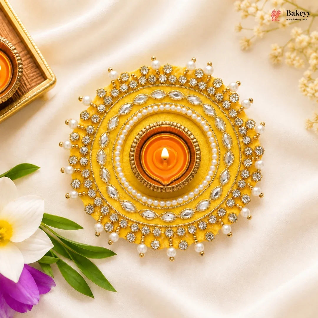Decorative yellow and silver lamp with a lit candle on a light background, featuring Bakey brand.