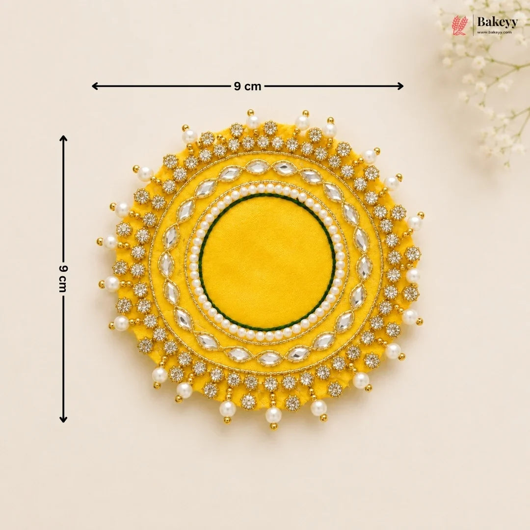 Decorative yellow circular piece with pearl and gemstone details, shown with measurements on a beige background.